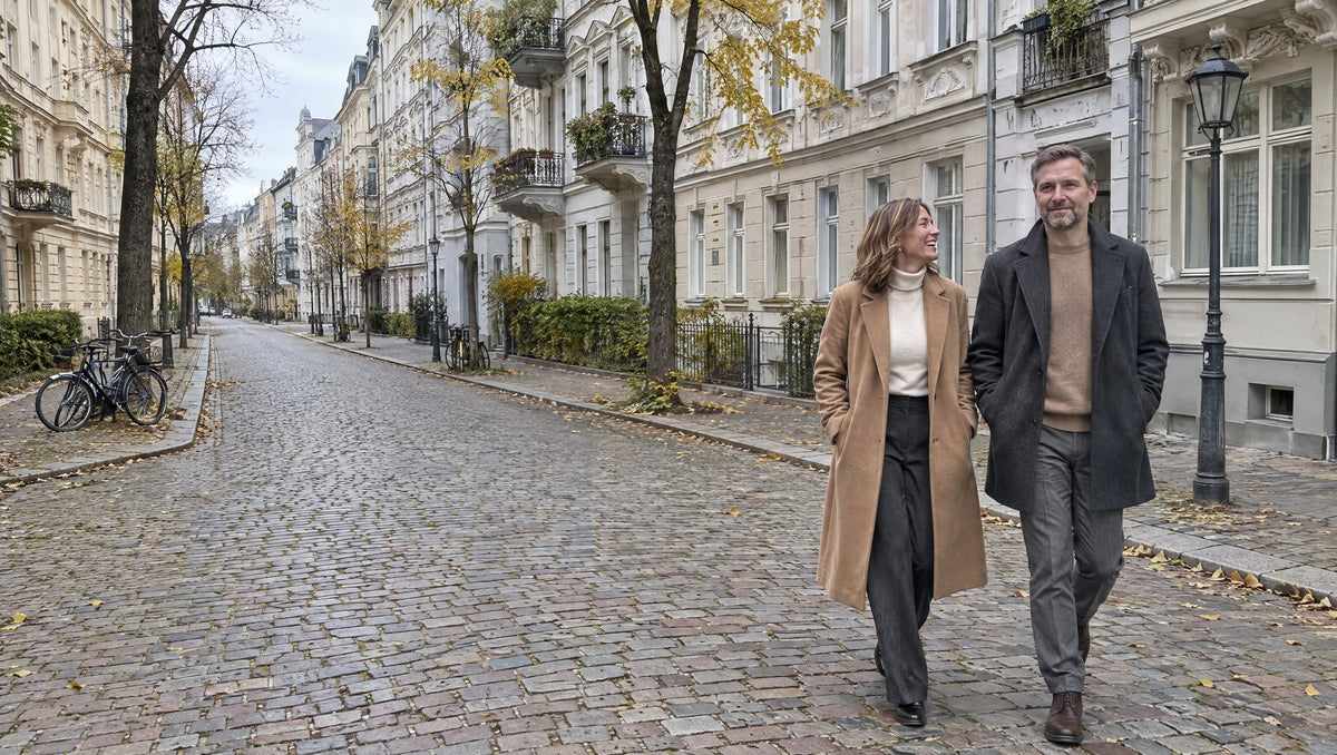 Frau im kamelfarbenen Mantel und Mann im anthrazitfarbenen Mantel in einer herbstlichen Altbau-Allee