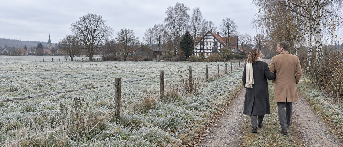 Paar in Wintermänteln auf einem Feldweg an einem Raureif-Morgen