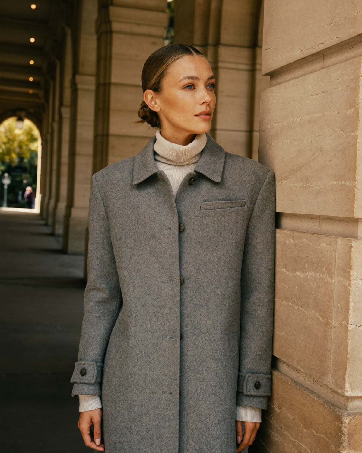 Damenmode für Herbst und Winter bei Tesslara: Frau in salbeigrauem Mantel und hellem Strick